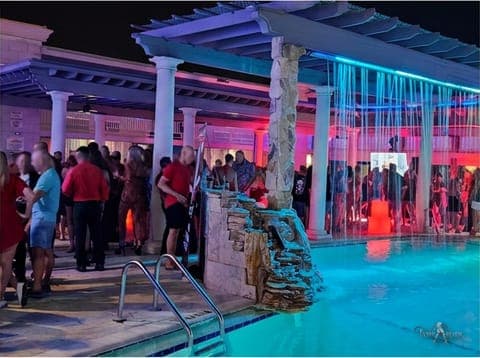 Guests gathered by the neon-lit pool and cabana at a TampArotic hotel-takeover — faces blurred for privacy.
