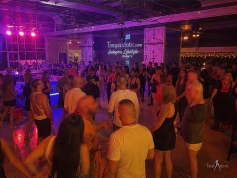 Guests dancing under the original event banner at an early TampArotic party — faces blurred for privacy.