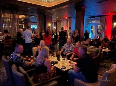 Couples relaxing in the velvet lounge booths at a TampArotic Tampa Bay event — faces blurred for privacy.
