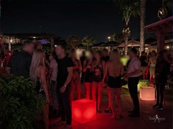 Guests socializing on the outdoor patio at dusk during a TampArotic night — faces blurred for privacy.