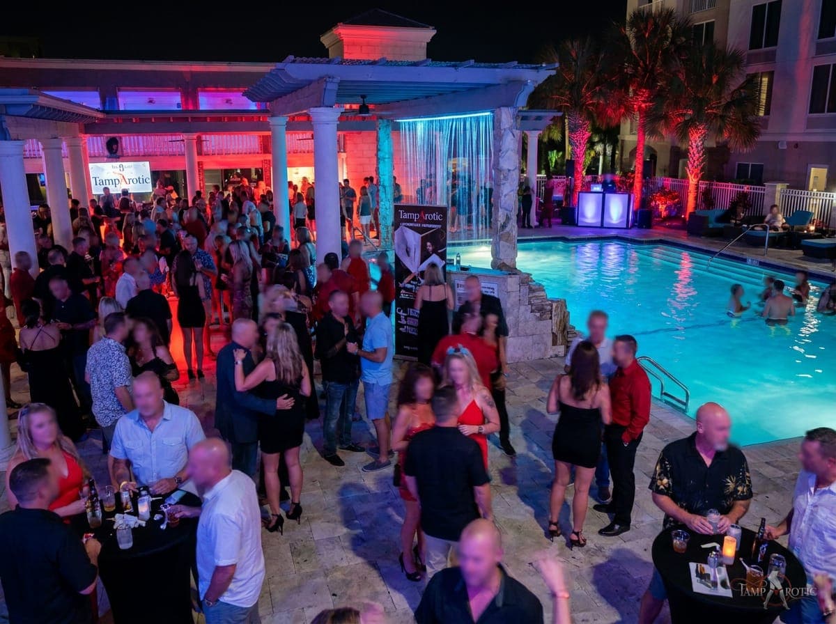 Guests filling the pool deck and pergola bar at a TampArotic hotel-takeover pool party in Tampa Bay — faces blurred for privacy.