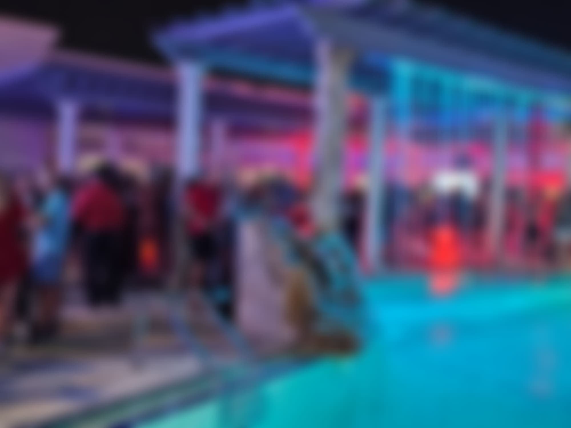 A TampArotic poolside night party under a lit pergola — guests blurred for privacy